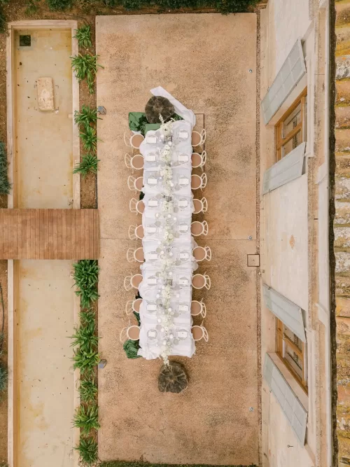 Overhead view of a long wedding table at Fontsanta with white florals, candles and symmetrical courtyard layout.