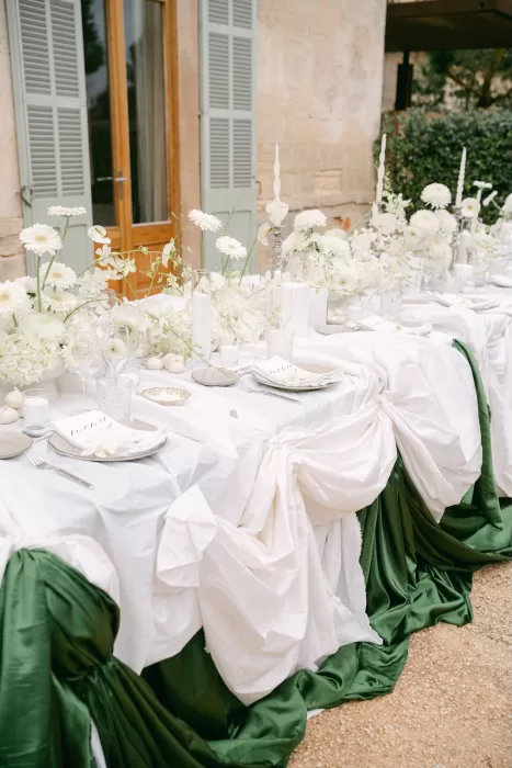 Elegant wedding head table at Fontsanta with white florals, candles and green draped linens set against the historic stone façade.