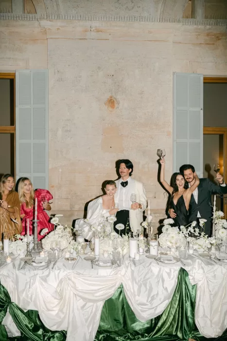 Wedding guests celebrating at the head table at Fontsanta with lush white florals and candlelight.