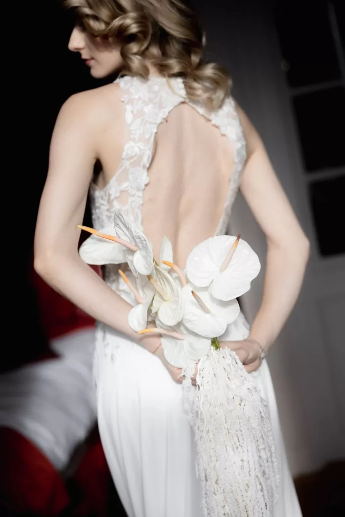 Back view of the bride holding a cascading bouquet inside a Grand Hotel du Lac suite, highlighting lace details and soft textures.