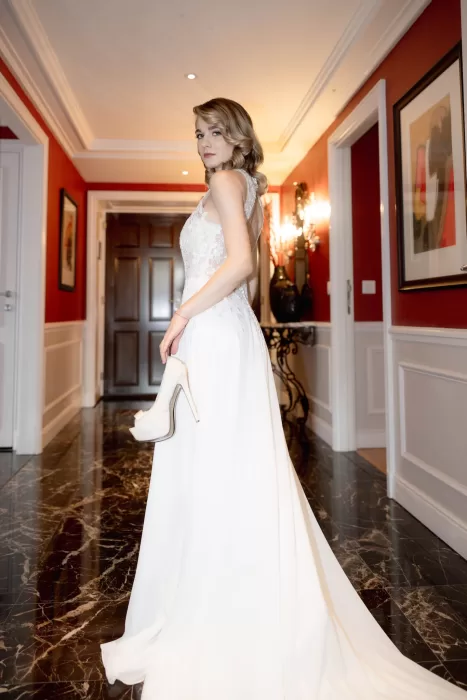 Bride holding her heels in a richly coloured hallway at Grand Hotel du Lac, styled with classic elegance and soft evening light.