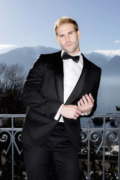 Groom portrait on a balcony at Grand Hotel du Lac with lake and mountain views in soft daylight.
