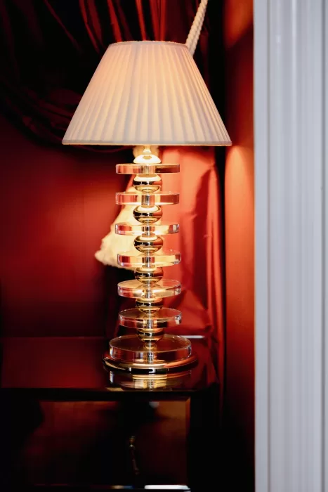 Sculptural table lamp glowing against deep red walls inside a Grand Hotel du Lac suite, highlighting the hotel’s refined interiors.