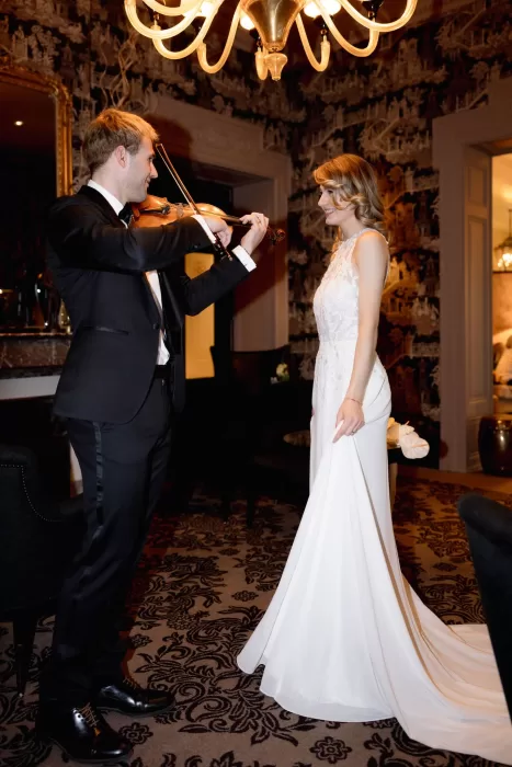 Groom playing the violin for the bride inside an intimate room at Grand Hotel du Lac during the wedding celebration.