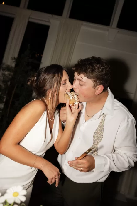 The couple share a playful cake bite during their wedding reception at The Greenhouse at Arrows Farm.