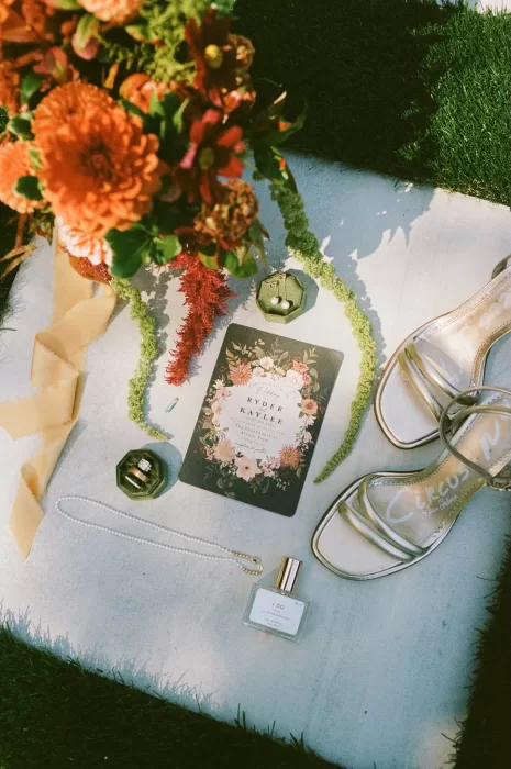 Wedding flat lay featuring stationery, rings, florals, and accessories styled on the ceremony aisle at The Greenhouse at Arrows Farm.