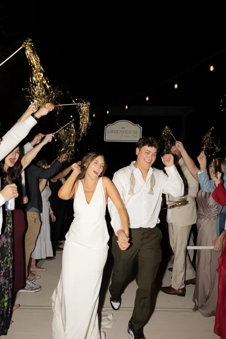 The couple make a joyful nighttime exit at The Greenhouse at Arrows Farm, surrounded by cheering guests and sparklers.