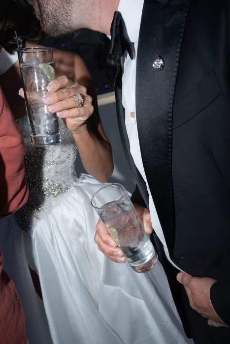 Close-up of the bride and groom holding drinks during an elegant evening reception at Islet Santorini.