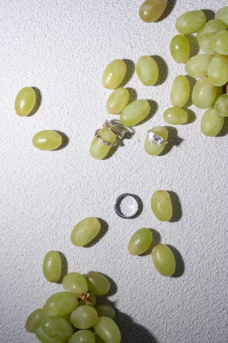 Wedding rings styled with fresh green grapes in a minimalist flat lay inspired by the setting of Islet Santorini.