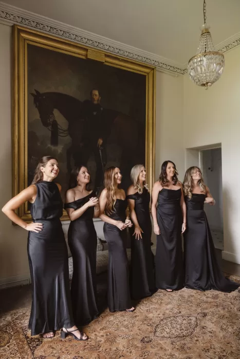 Bridesmaids in black dresses standing together inside the elegant interiors of Boturich Castle.