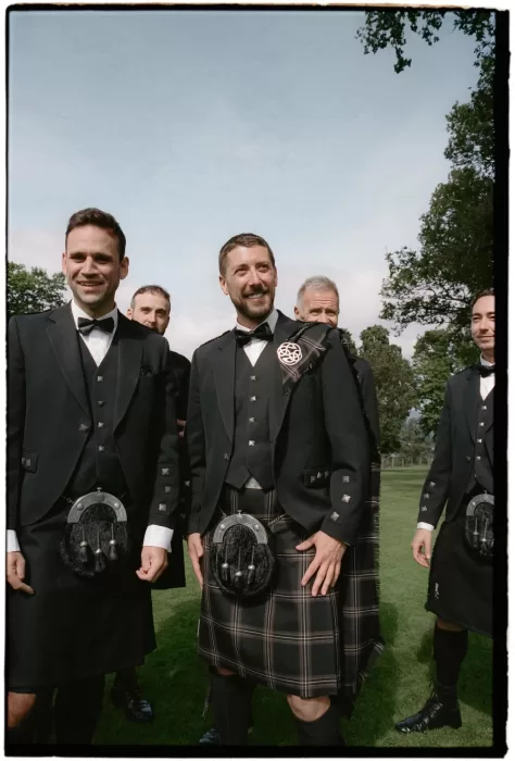 Groomsmen wearing traditional kilts on the lawn at Boturich Castle before the ceremony.