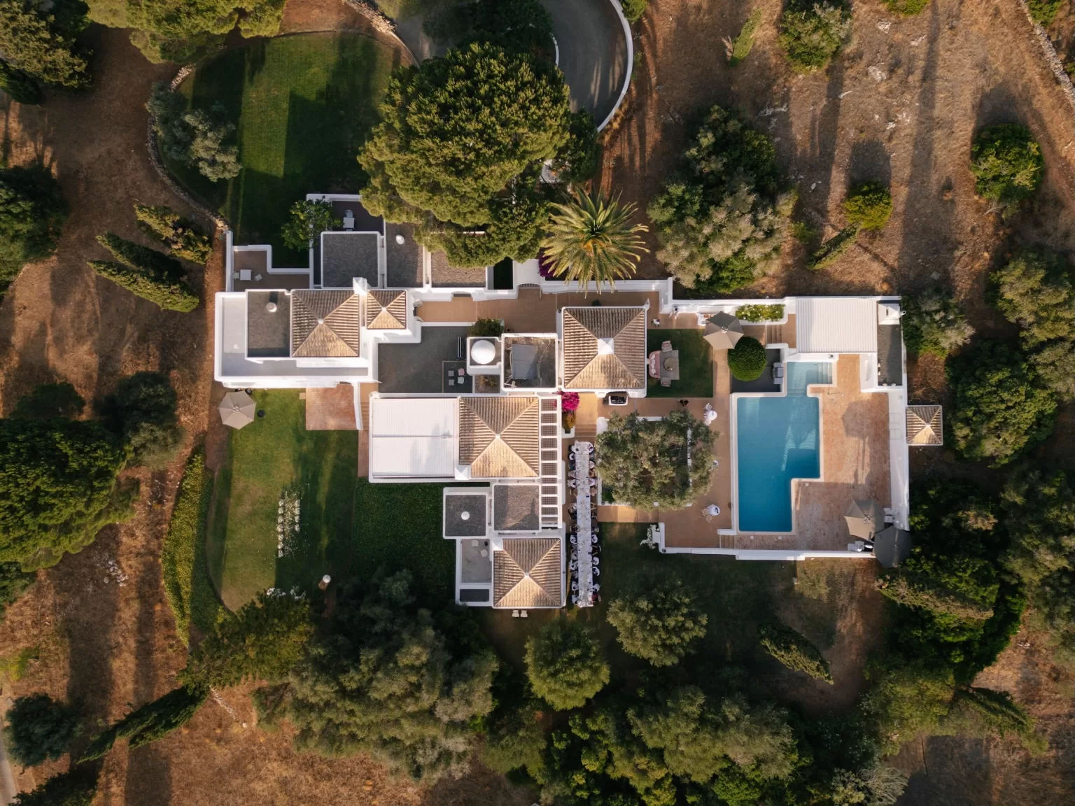 Aerial top-down view of Casa Arte showing the pool, terraces, gardens, and surrounding countryside in golden afternoon light.