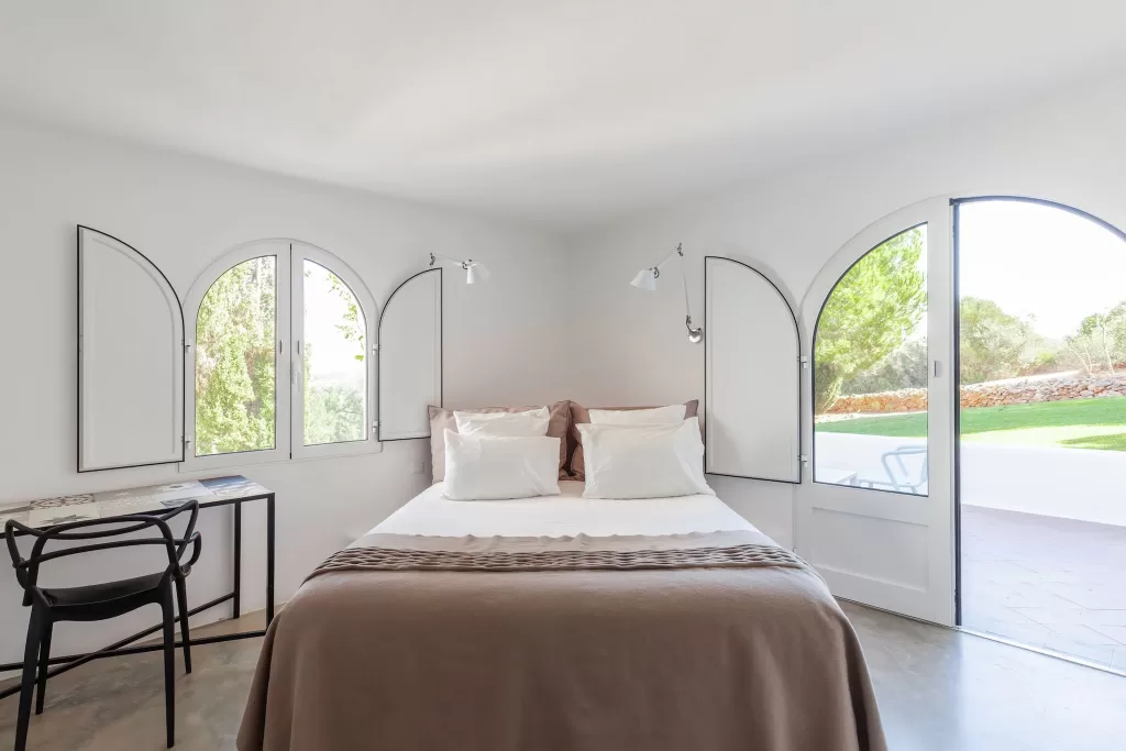 Bright guest bedroom with arched windows and terrace access at Casa Arte Lagos, designed in a relaxed Mediterranean style.