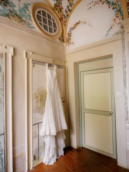 Wedding dress hanging inside a frescoed room at Castello di Celsa before the ceremony.