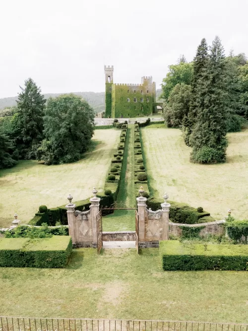 Ivy-covered castle tower at Castello di Celsa framed by rolling Tuscan landscape and formal lawns.