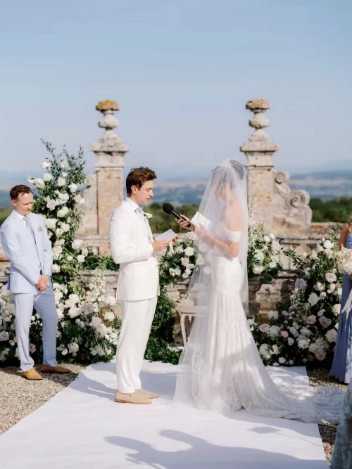 Outdoor wedding ceremony on the terrace of Castello di Celsa with floral arrangements and panoramic Tuscan views.