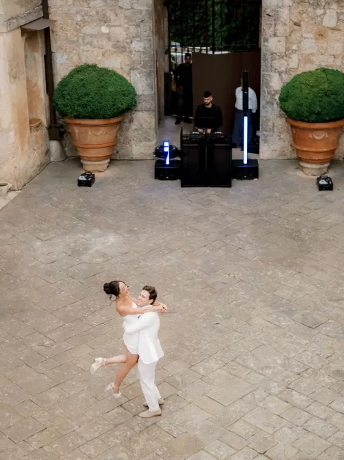 Bride and groom spinning during their first dance in the stone courtyard at Castello di Celsa with DJ setup behind them.