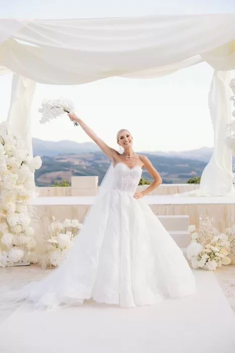 Bride celebrating with bouquet beneath white draped ceremony canopy at Castello di Velona.