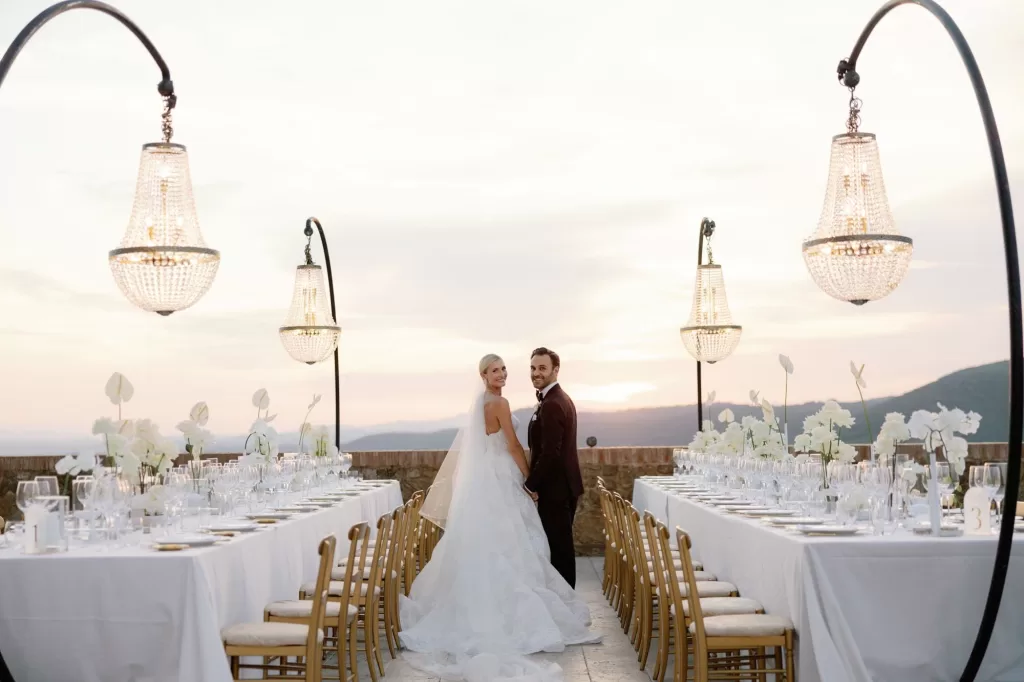 Symmetrical outdoor reception layout with chandeliers at sunset at Castello di Velona.