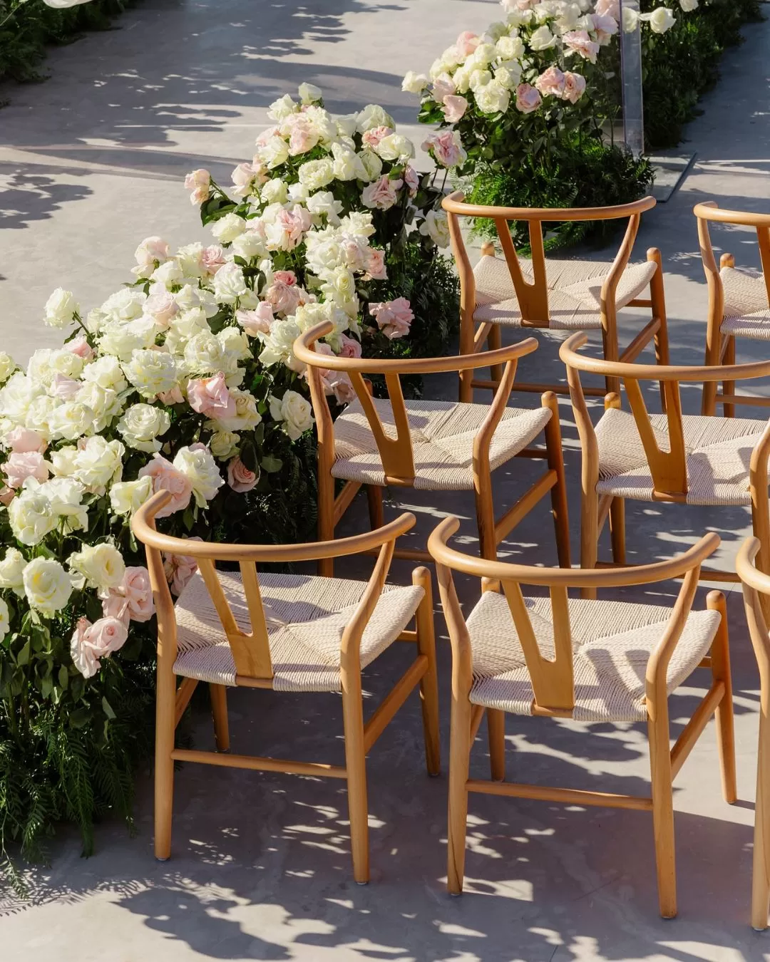 Minimalist white wedding chairs arranged at Cavo Ventus, overlooking the Santorini coastline for a dreamy ceremony.