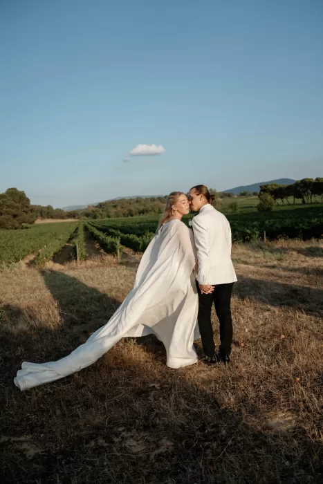Bride and groom holding hands in the vineyards at golden hour at Château Canet, rolling hills and long shadows creating a romantic Provençal backdrop.