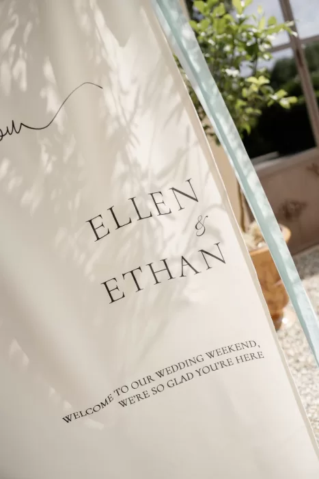 Elegant wedding welcome sign for Ellen and Ethan displayed outdoors at Château Canet, with soft sunlight and olive trees creating a refined Provençal atmosphere.