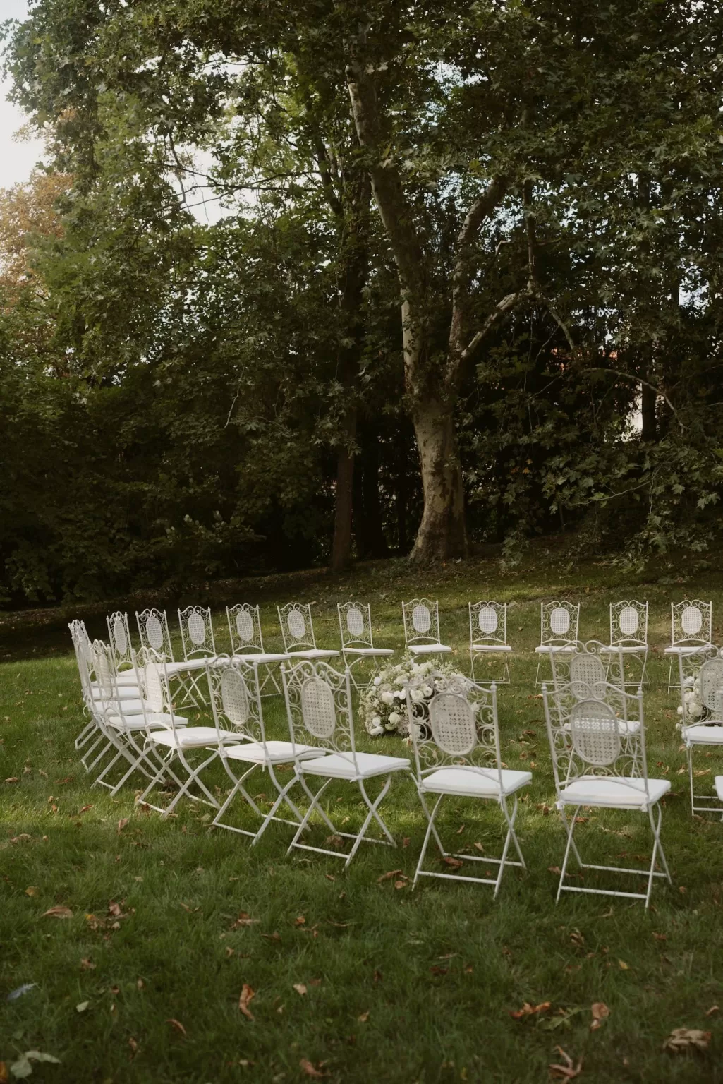 White chairs arranged on the lawn for an outdoor ceremony at Château du Prieuré d’Evecquemont.