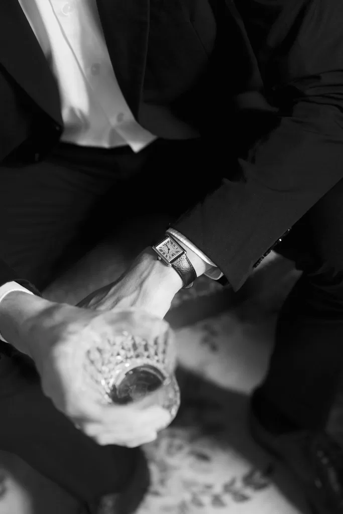 Black and white detail of the groom’s watch and glass, capturing a refined pre-ceremony moment.