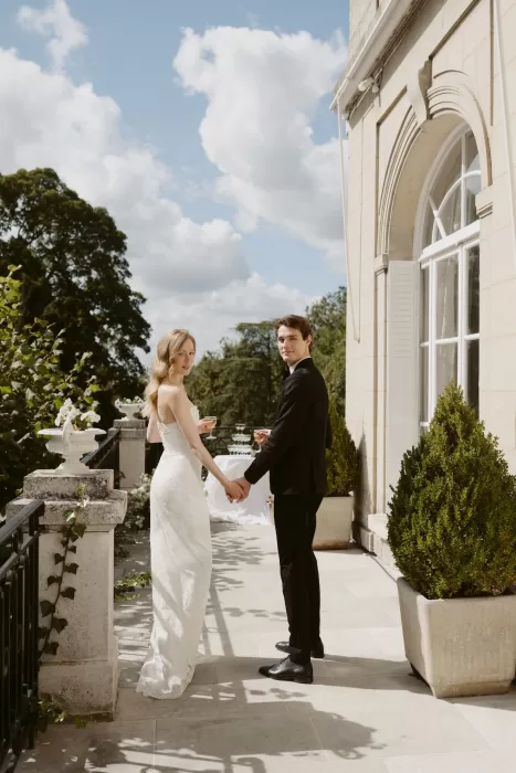 Bride and groom holding hands on the terrace at Château du Prieuré d’Evecquemont, overlooking the gardens.