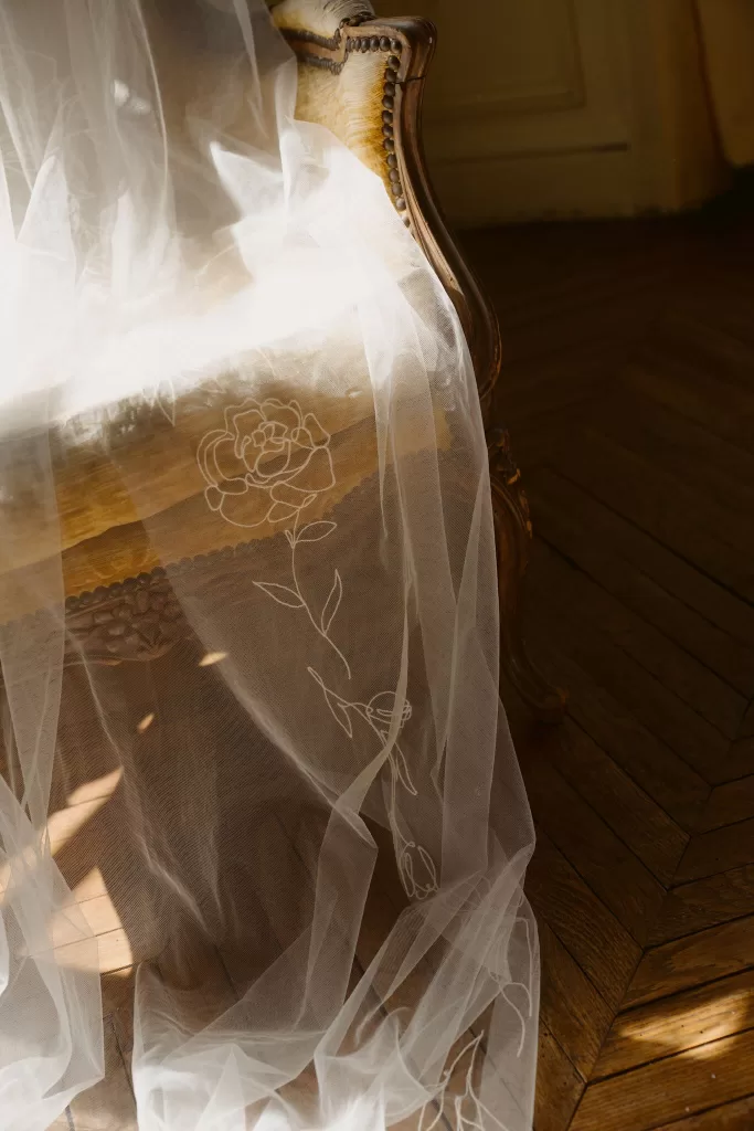 Delicate bridal veil draped over an antique chair inside Château du Prieuré d’Evecquemont.