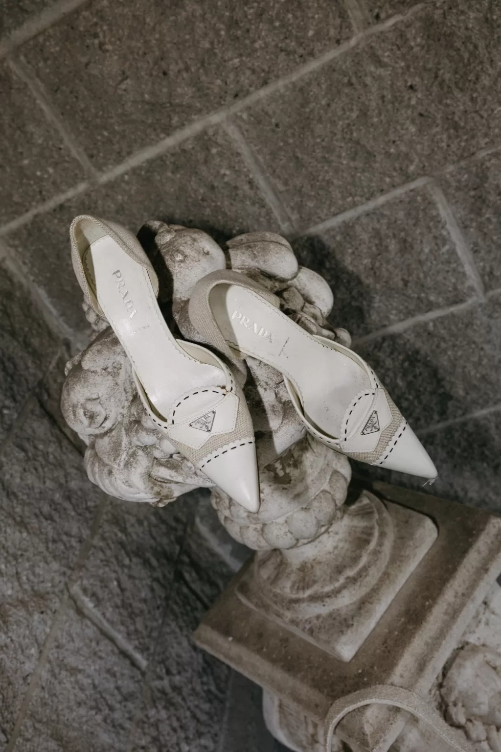 Elegant bridal Prada shoes displayed on a stone pedestal at Chateau Lill, captured in soft evening light.