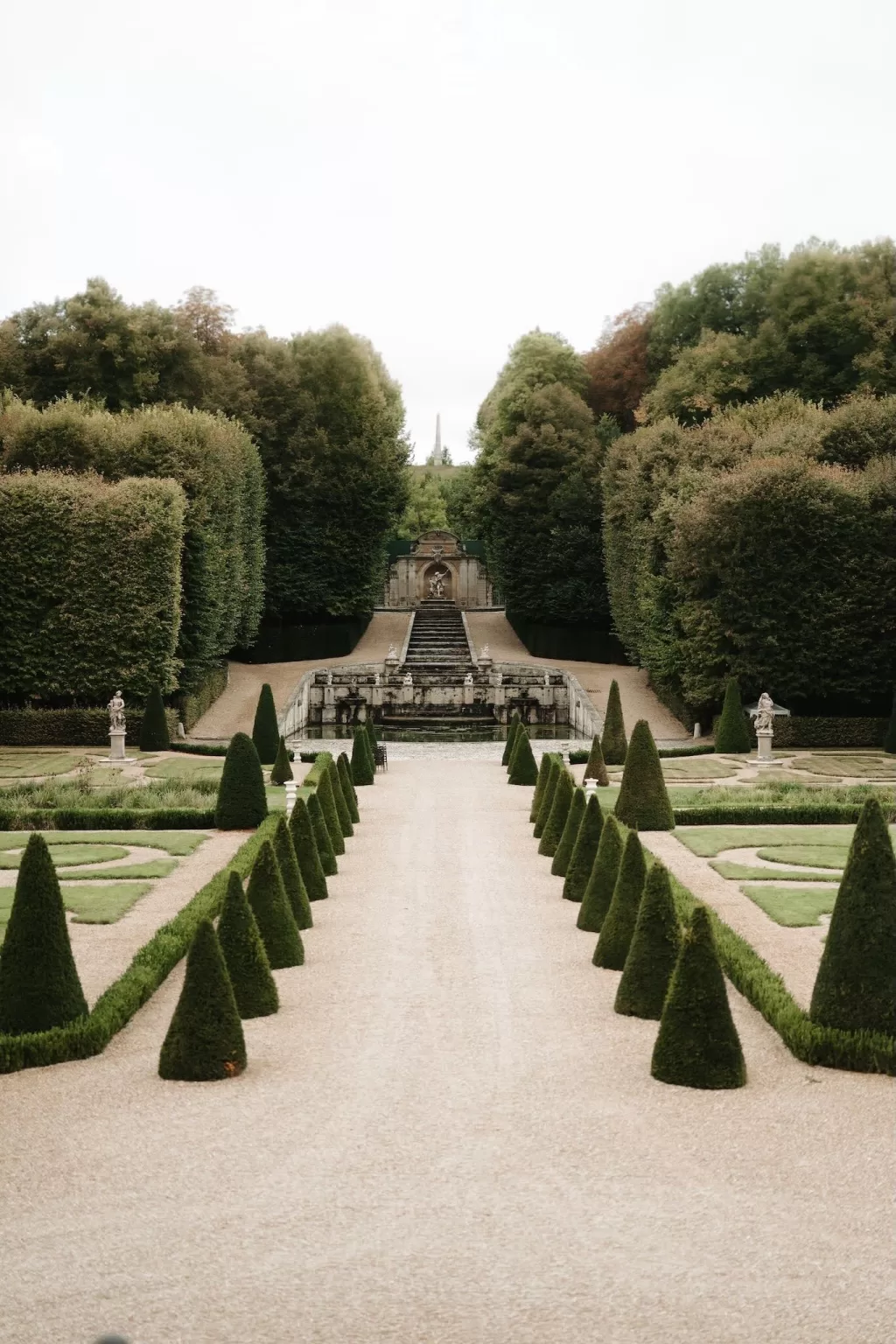 Symmetrical garden path and sculpted hedges leading to the grand staircase and fountain at Château de Villette.