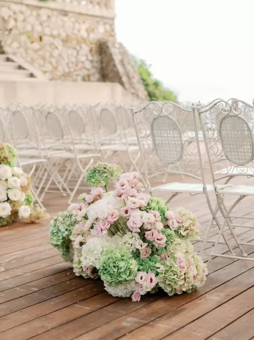 Soft pastel floral arrangements placed along the ceremony aisle at Domaine de Canaille