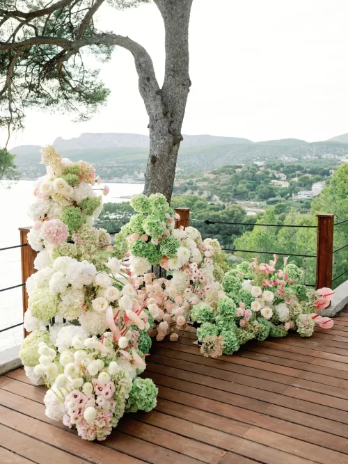 Soft pastel floral arrangements placed along the ceremony aisle at Domaine de Canaille