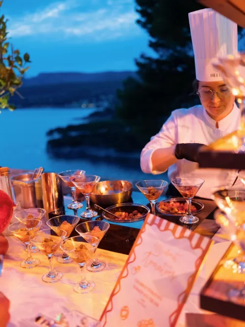 Chef preparing cocktail canapés at an outdoor evening reception overlooking the sea at Domaine de Canaille
