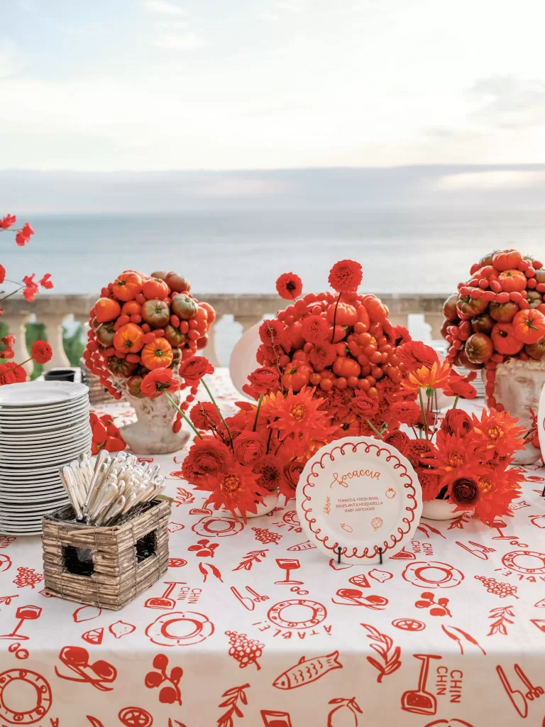 Wedding reception table with bold red floral arrangements and illustrated linens at Domaine de Canaille