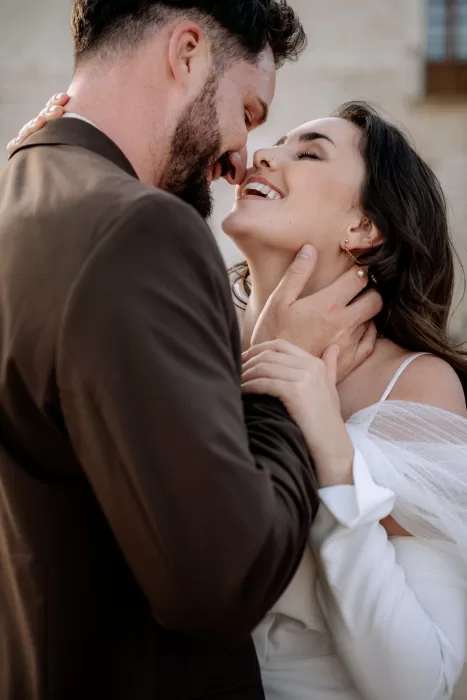 Joyful close portrait of the bride and groom at Finca Morneta, smiling as golden light highlights their faces.