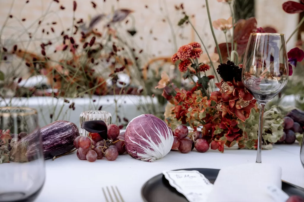 Close-up of reception styling at Finca Morneta with grapes, seasonal produce and textured floral arrangements across the table.