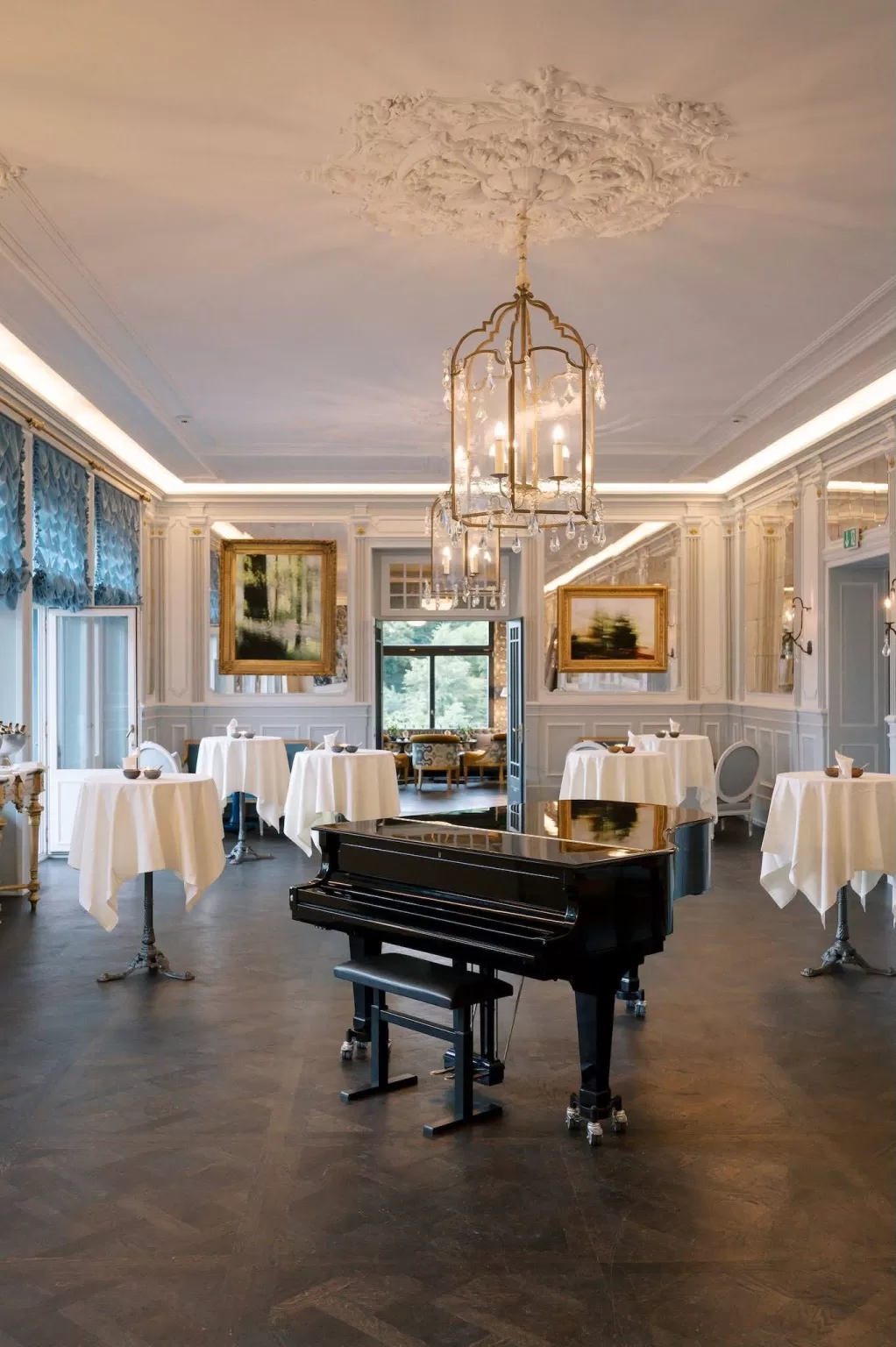 Refined ballroom at Hotel Château Gütsch with chandeliers, gold accents, and a grand piano.