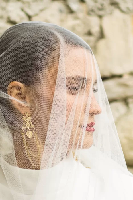 Close-up bridal portrait at Hotel Ristorante La Darsena, veil softly draped over her face against a stone wall backdrop.