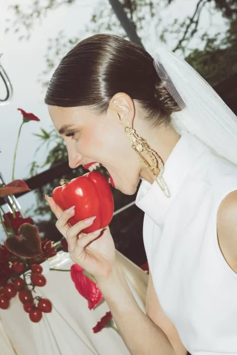 Bride in sleek white dress playfully holding a red pepper during wedding styling shoot at Hotel Ristorante La Darsena.