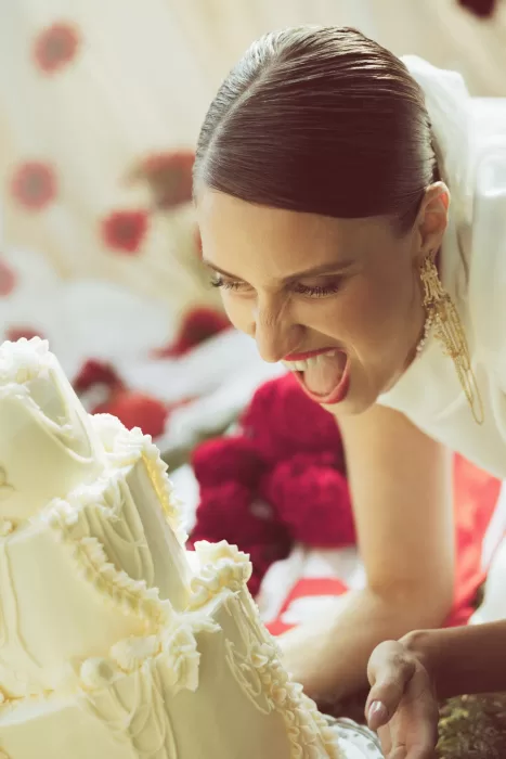 Bride leaning toward wedding cake in playful moment during lakeside celebration at Hotel Ristorante La Darsena.