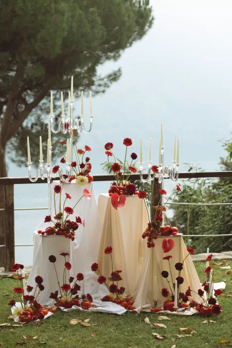 Ceremony styling with red florals and glass candelabras arranged on terrace lawn at Hotel Ristorante La Darsena with lake views.