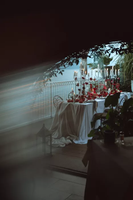 Candlelit reception table with red florals and draped linens on terrace at Hotel Ristorante La Darsena overlooking Lake Como at dusk.