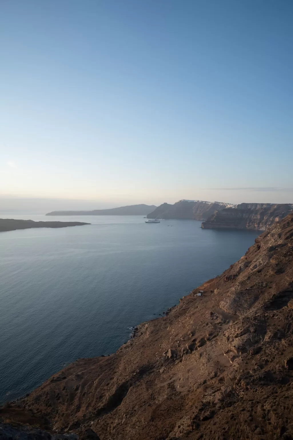 Panoramic caldera and sea view from Islet Santorini during golden hour, highlighting the venue’s natural setting.