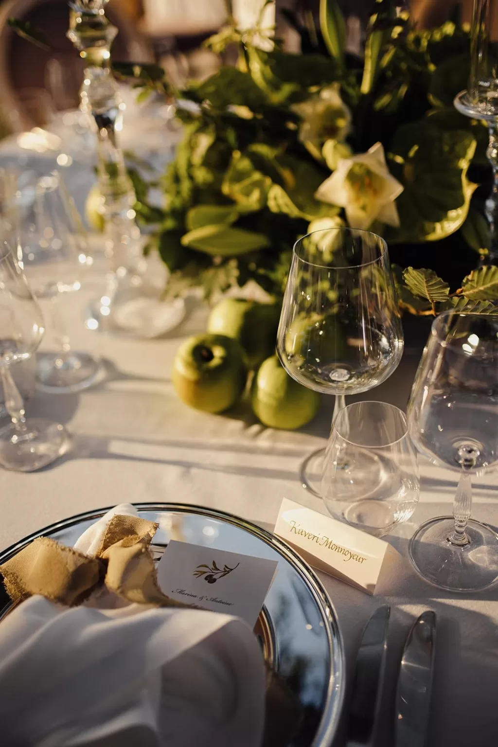 Refined place setting with silver charger and olive motif at a Meneghetti Wine Hotel wedding reception.
