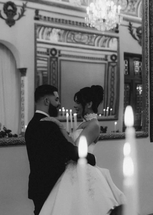 Black and white portrait of the couple embracing at Palacio Metropolitano with candlelight glowing in the mirrored background.