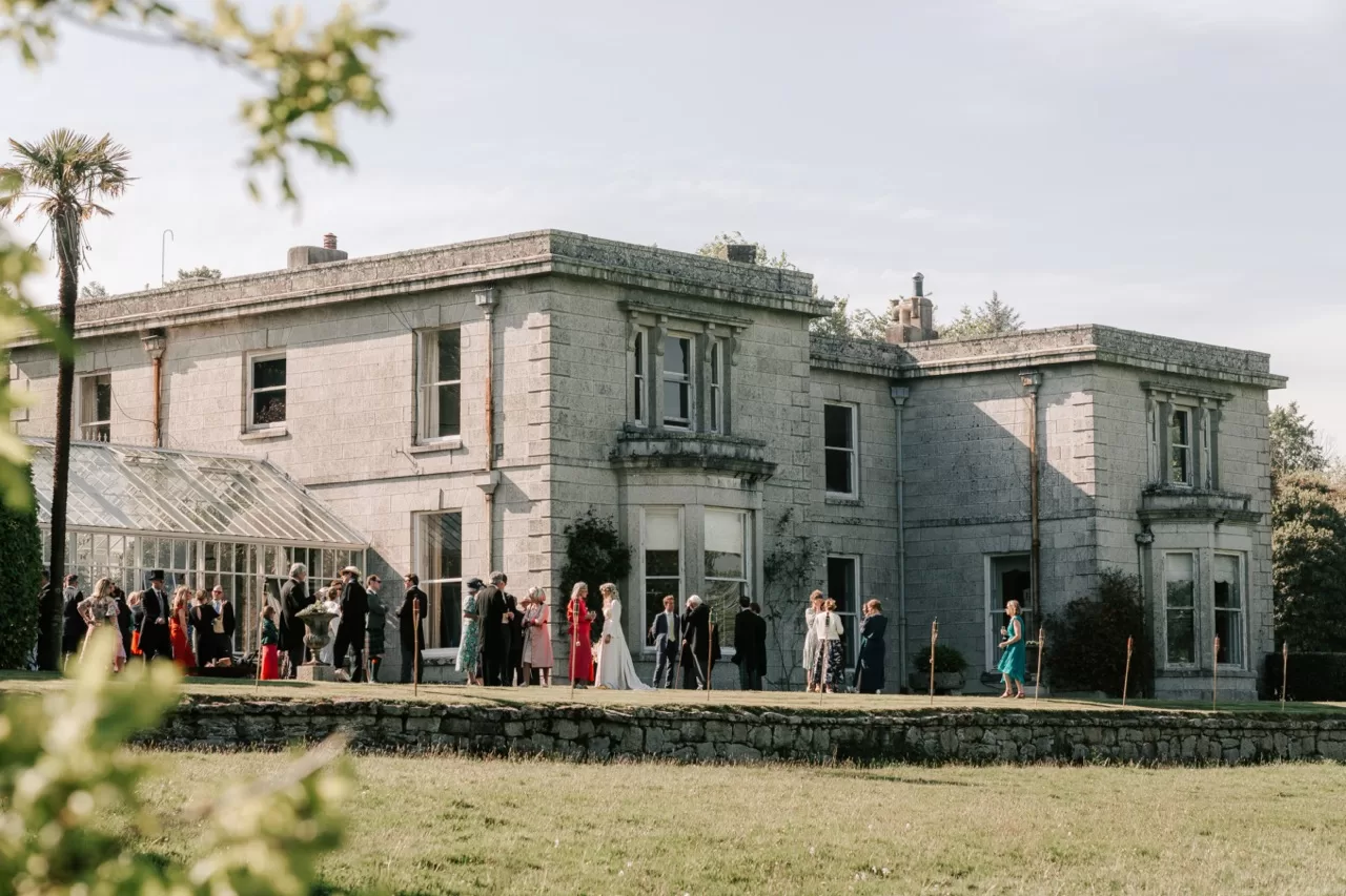 Guests gathered on the lawn outside the conservatory at Scorrier House during a relaxed drinks reception.