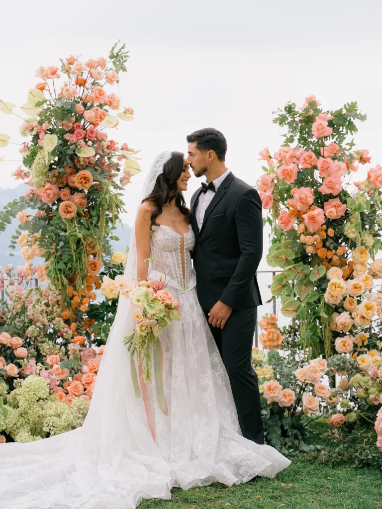 Romantic bride and groom portrait surrounded by abundant peach floral arrangements, photographed by Sim Sawyers Photography