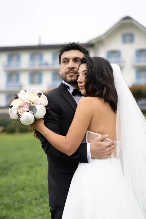 Bride and groom embracing on the lawns of Villa Honegg with the elegant hotel façade in the background.